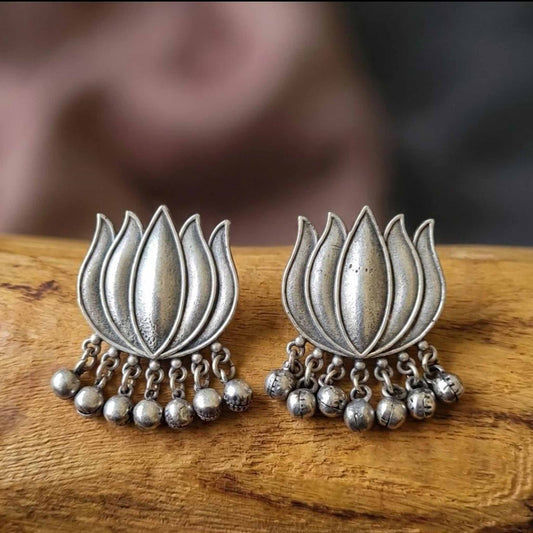 Lotus ghunghru stud earrings displayed on wooden surface