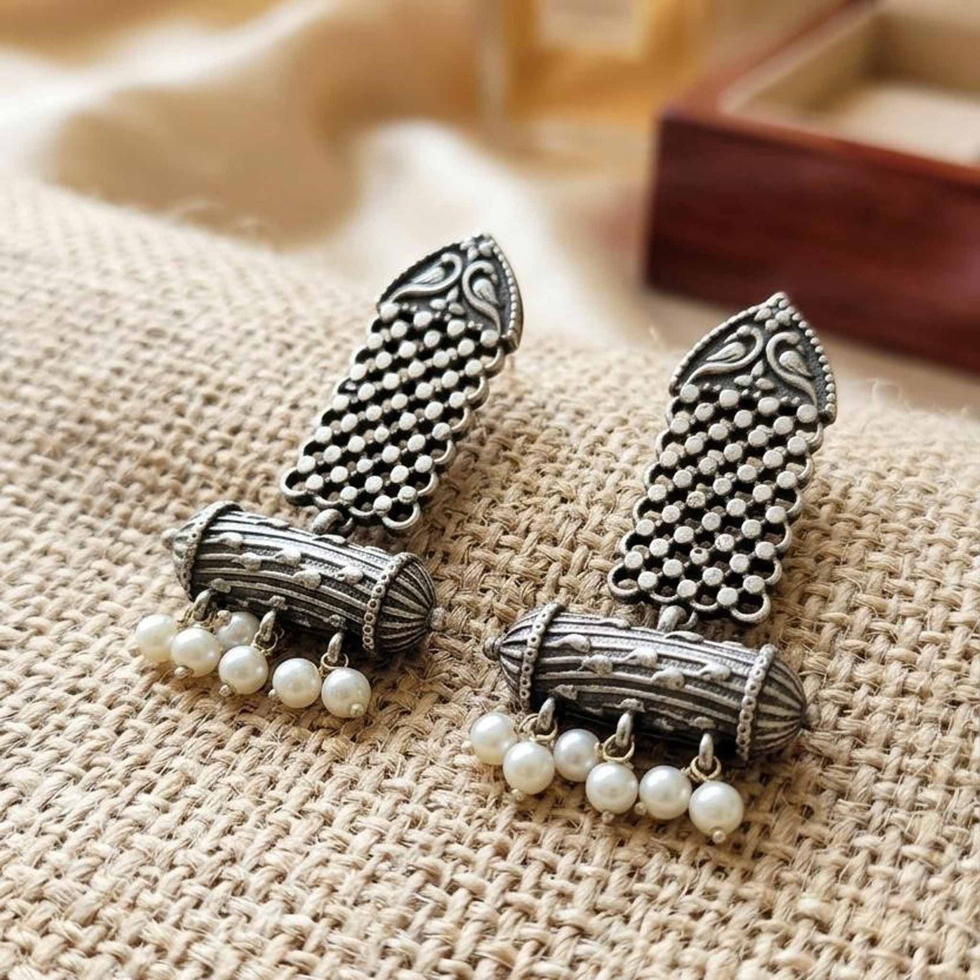 Close-up heritage pearl dangler earrings on fabric background