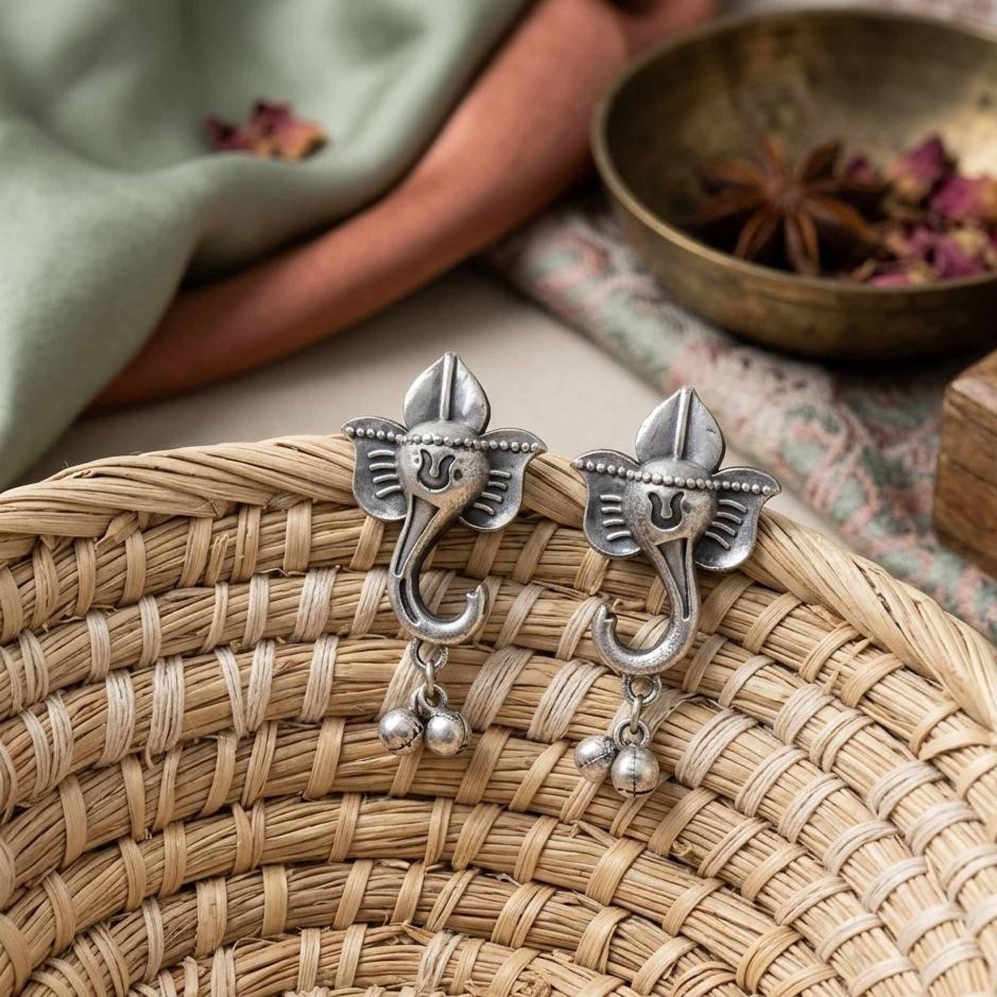 Traditional Ganesha earrings displayed on woven basket
