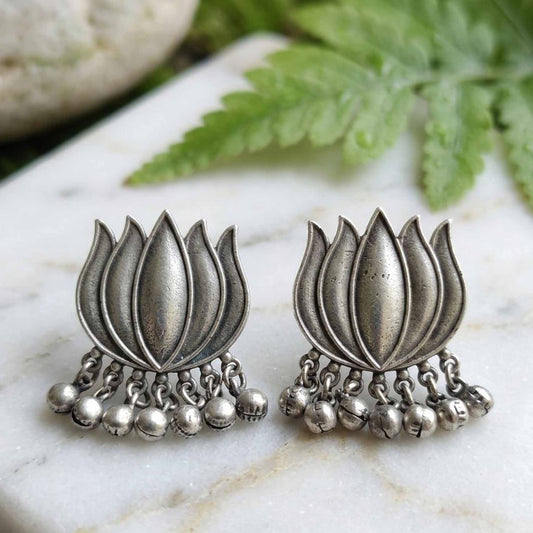 Oxidised lotus ghunghru earrings displayed on marble background