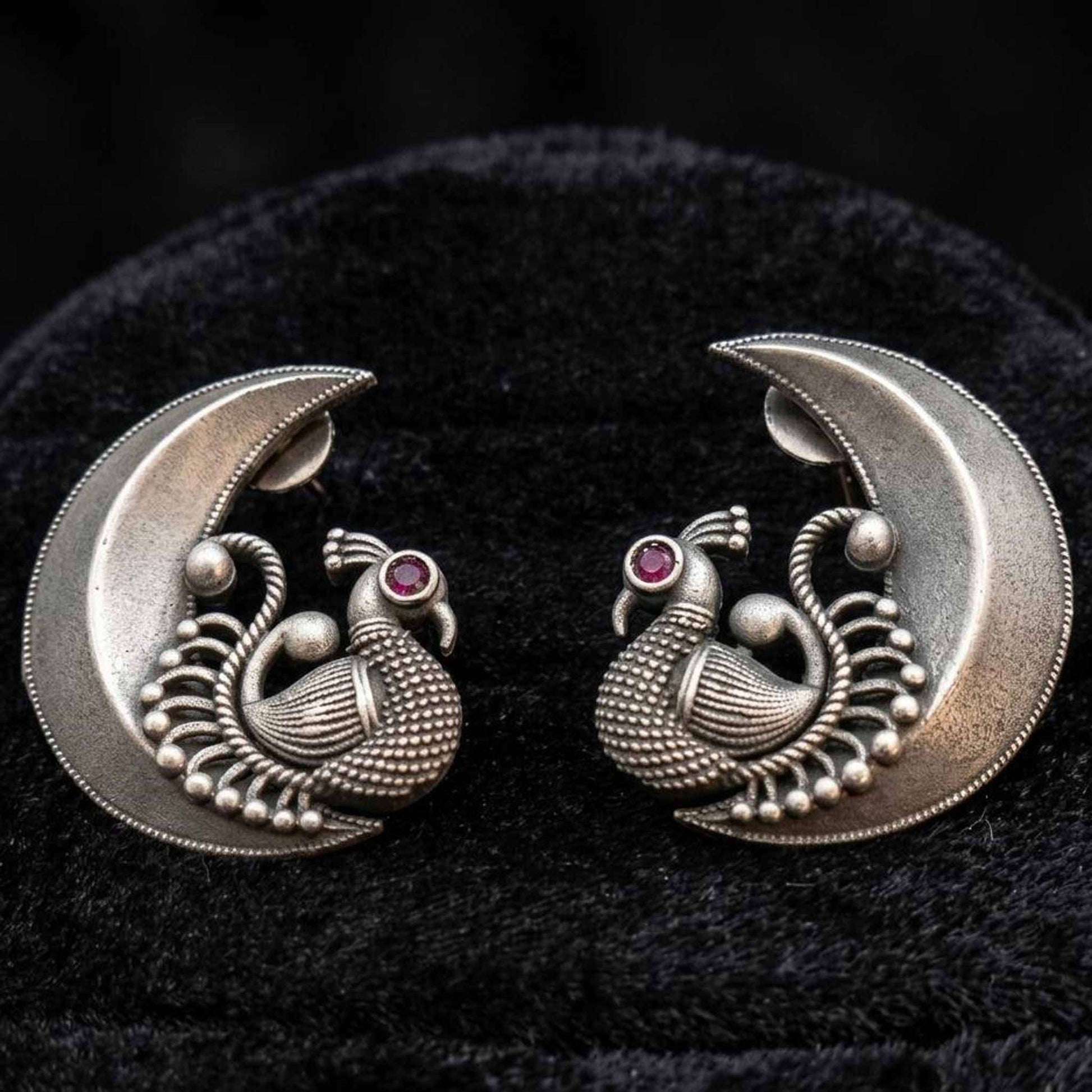 Closeup of peacock moon stud earrings on velvet background