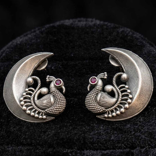 Closeup of peacock moon stud earrings on velvet background